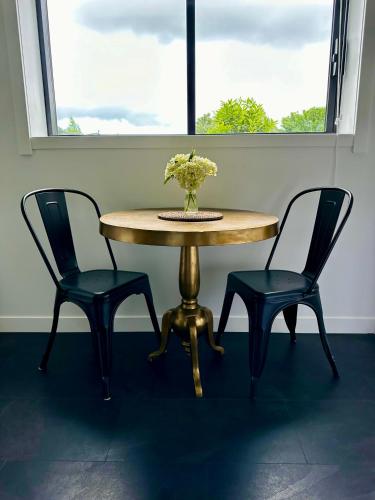 a table with two chairs and a vase with flowers on it at Matamata Country B&B in Matamata