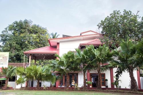 a house with palm trees in front of it at Golden Star Guest House in Jaffna