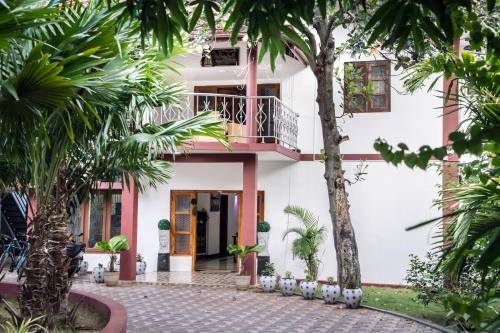 uma casa branca com varanda e palmeiras em Golden Star Guest House em Jaffna