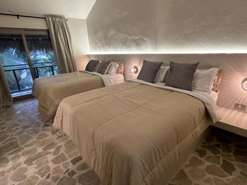 Dos camas en un dormitorio con dos lámparas. en El Rincon de Abi, en Las Terrenas