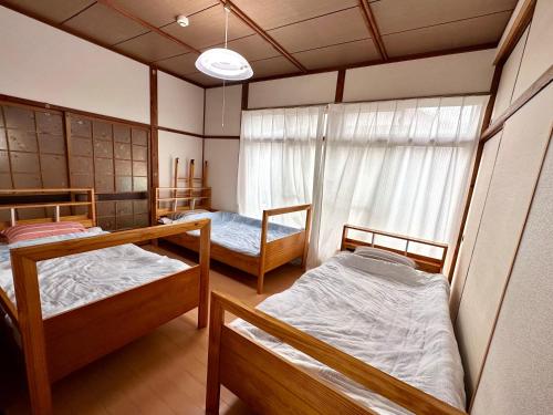 Guest House Island في Wakamatsu: غرفة بها ثلاثة أسرة بطابقين ونافذة