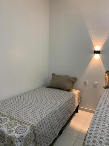 a small bedroom with a bed and a lamp at Sol do Caribe Suítes in Maragogi