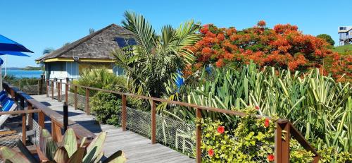 a wooden walkway leading to a house with flowering plants at Beach House Lodge in Poum