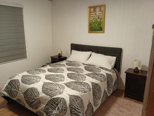 ein Schlafzimmer mit einem Bett mit einer schwarz-weißen Bettdecke in der Unterkunft Casa Cudico bajo- Lican ray in Villarrica