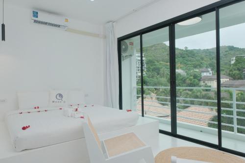uma casa de banho branca com uma banheira e uma grande janela. em MoonE em Ka Rorn