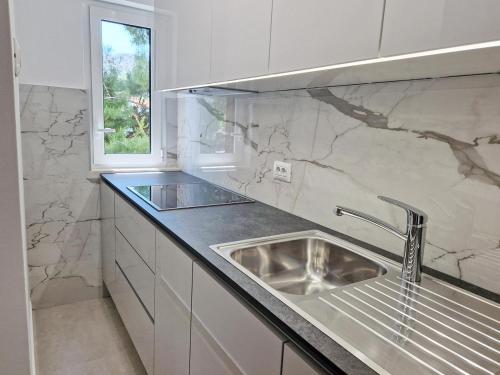 biała kuchnia ze zlewem i oknem w obiekcie Apartments with a parking space Baska, Krk - 18793 w Bašce
