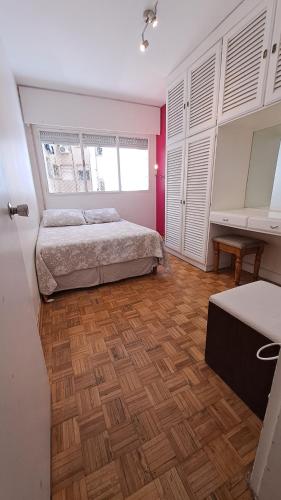1 dormitorio con 1 cama y suelo de madera en DepArt en Rambla Punta Carretas, en Montevideo