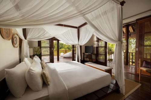 a bedroom with a large white bed with curtains at Jimbaran Beach Villas by Nakula in Jimbaran