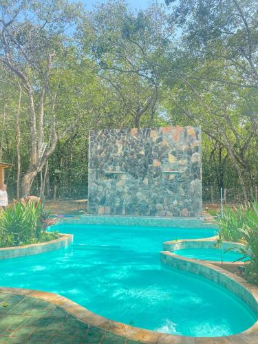una piscina con una pared de piedra y agua azul en Casa Amarela en Pirenópolis