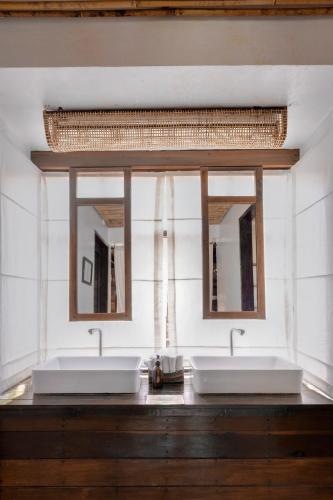 a bathroom with two sinks and two mirrors at Harana Surf Resort in General Luna