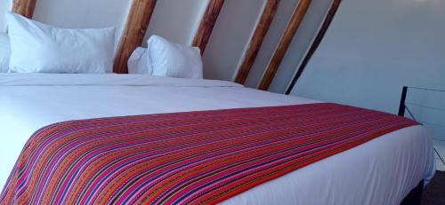 een bed met een kleurrijke gestreepte deken erop bij Runa Apartamentos in Cuzco