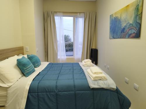 a bedroom with a large blue bed with a window at Marejada in Comodoro Rivadavia
