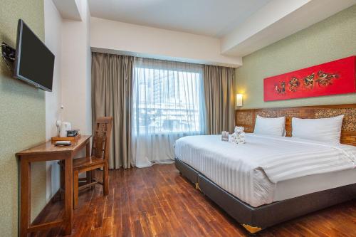 Habitación de hotel con cama, escritorio y TV. en 1O1 URBAN Jakarta Thamrin, en Yakarta
