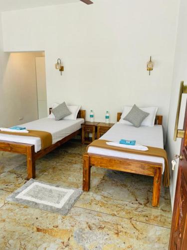 a bedroom with two beds and a mirror at SALT LIFE MARARI BEACH VILLA in Mararikulam