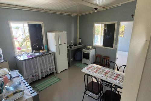 a kitchen with two tables and a white refrigerator at Casa Dom Aquino in Chapada dos Guimarães