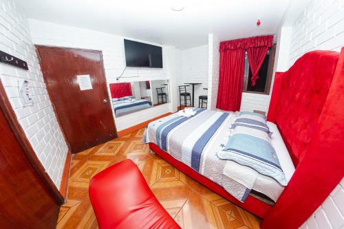 1 dormitorio con cama roja y silla roja en Hostal Waya, en Lima