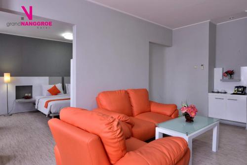 a living room with an orange couch and a bed at Hotel Grand Nanggroe in Banda Aceh