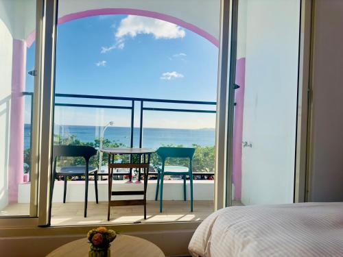 a bedroom with a large window with a table and chairs at 南灣陽光皮小妞 Pii hostel in Nanwan
