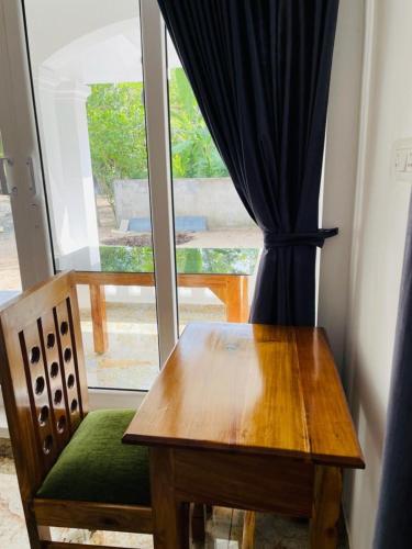 a wooden table and chair in front of a window at SALT LIFE MARARI BEACH VILLA in Mararikulam