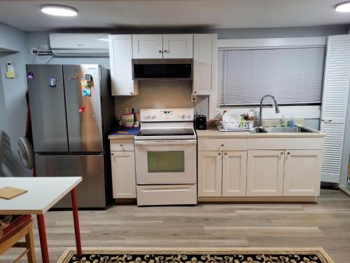 uma cozinha com armários brancos e um frigorífico de aço inoxidável em The Dune Beach House em Norfolk