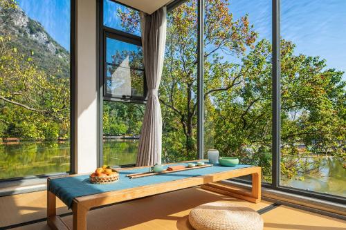ein Wohnzimmer mit großen Fenstern und einem Tisch in der Unterkunft Guilin HeShe Lakeside Resort in Guilin
