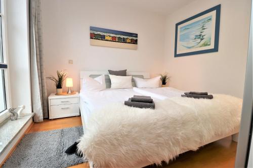 ein Schlafzimmer mit einem weißen Bett mit einer weißen Decke in der Unterkunft Birkenhof App 74 in Wustrow