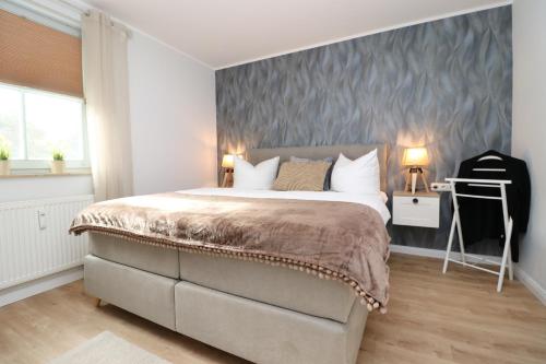 una camera da letto con un grande letto con una parete grigia di Oewern Diek App 10 a Wustrow