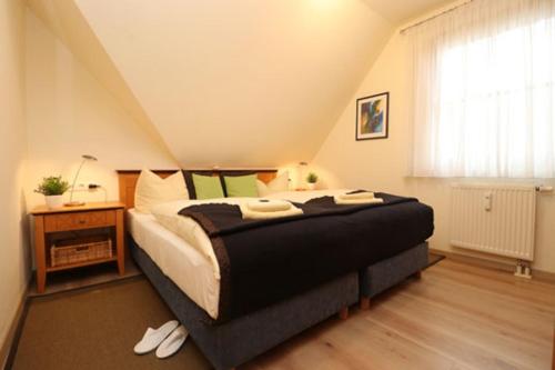 a bedroom with a bed and a table and a window at Oewern Diek App 05 in Wustrow