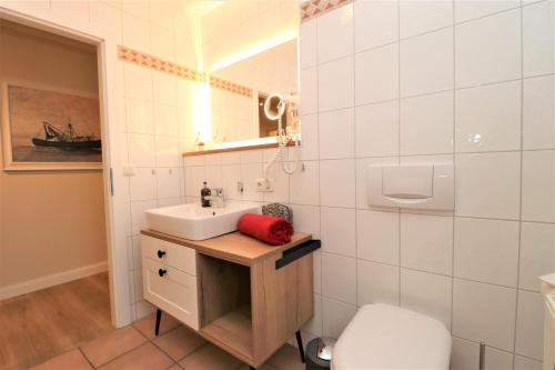 ein Badezimmer mit Waschbecken, Toilette und Spiegel in der Unterkunft Oewern Diek App 58 in Wustrow