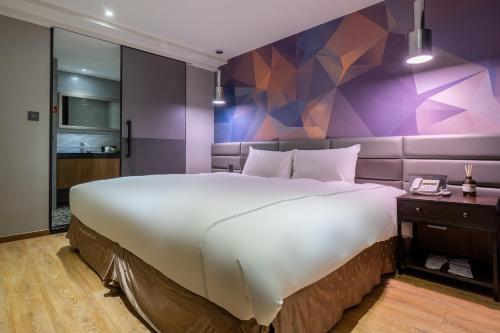 a bedroom with a large bed and a purple wall at CHECK inn Taichung Wenxin Zhongqing in Taichung