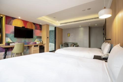 a hotel room with two beds and a desk at CHECK inn Taichung Wenxin Zhongqing in Taichung