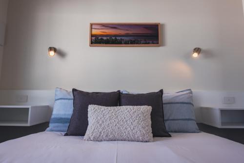 a bed with pillows and a picture on the wall at BIG4 Ulladulla Beachside Holiday Park in Ulladulla