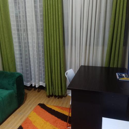ナイロビにあるShanDezのデスク、緑のソファ、カーテンが備わる客室です。