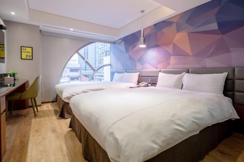 two beds in a hotel room with a geometric wall at CHECK inn Taichung Wenxin Zhongqing in Taichung