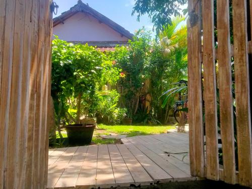 an open door to a garden with trees and plants at Little Elephant Cottage in Gili Trawangan