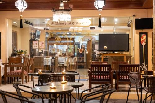 a restaurant with tables and chairs and a television at At Chiang Mai Hotel in Chiang Mai