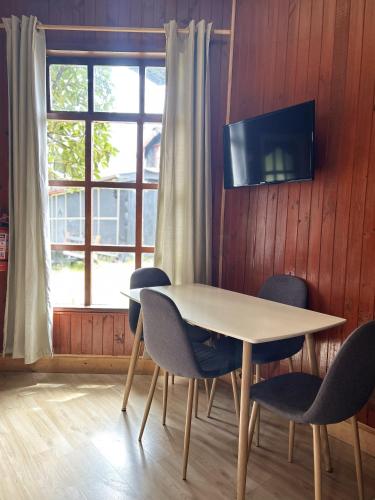 a table and chairs in a room with a window at QUELEN AUSTRAL in Hornopiren