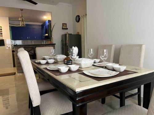mesa de comedor con sillas y mesa con copas de vino en Casa Paradis- secure, cozy& peaceful paradise in heart of most happening colony, en Jaipur