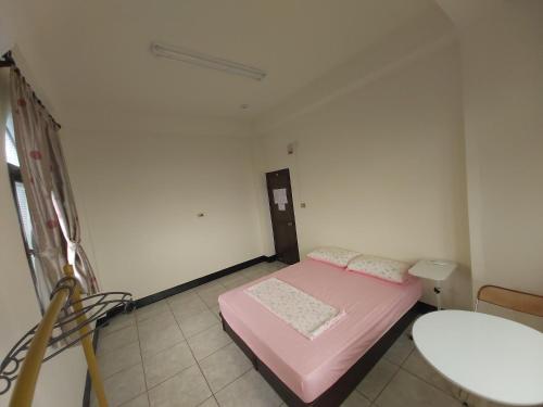 a small room with a pink bed and a table at Huan Bei 88 Homestay in Jincheng