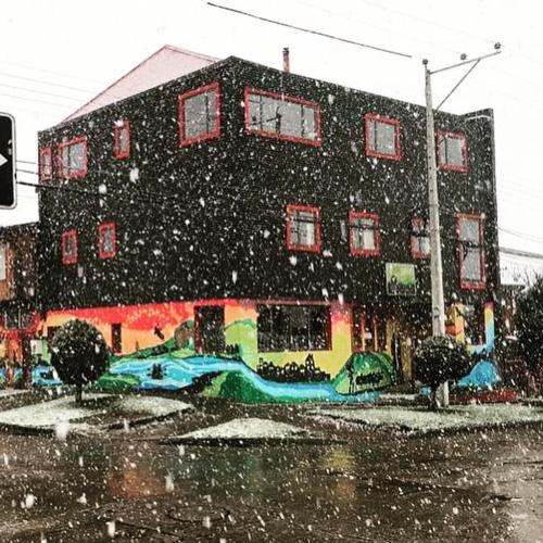 a building on a street in the snow at Hostal Esquina Patagónica in Coihaique