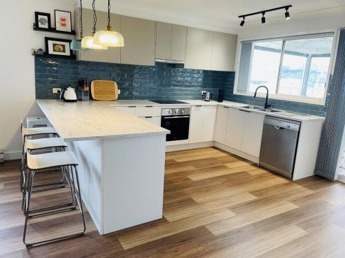 eine Küche mit weißen Schränken und einer Arbeitsplatte in der Unterkunft Rose's Cottage in Sanctuary Point