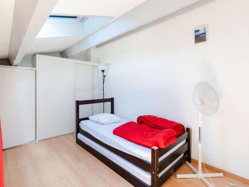 Cette chambre comprend un lit avec des draps rouges et un ventilateur. dans l'établissement Pavillon Climatisé avec Mezzanine, WIFI et Parking Privé - Gruissan Les Ayguades - FR-1-409-187, à Gruissan