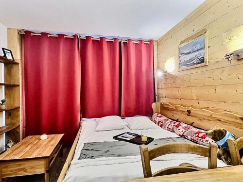 - une chambre avec des rideaux rouges, un lit et une table dans l'établissement Sublime T2 rénové, tout confort, proche centre Val Claret - FR-1-411-914, à Tignes