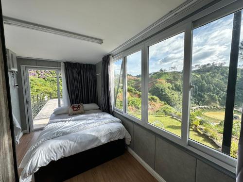 a bedroom with a bed and large windows with a view at Four Spring Villas & Golfs Da Lat in Da Lat