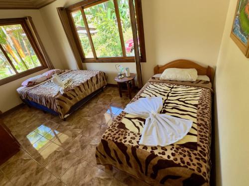two beds in a room with two windows at Cabina monteverde Soan de Montaña in Monteverde Costa Rica