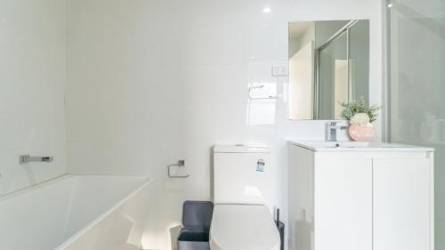 a white bathroom with a sink and a mirror at Central Canterbury Charm Sky View Free Parking in Sydney
