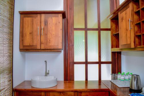 y baño con lavabo y armarios de madera. en Uma Garden Kandegedara, en Matugama