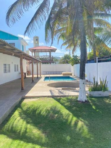 een tuin met een palmboom en een zwembad bij Cabaña con piscina y Cerca al mar VILLA CONEJO in Juan de Acosta