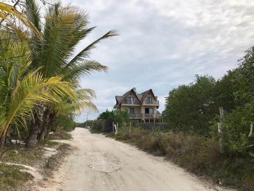 a house on a dirt road next to a palm tree at CasaCalma Great for families! in Holbox Island