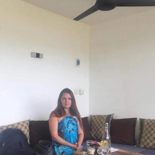 a woman in a blue dress sitting on a couch at AMIGOS BUNGALOWS GILI MENO in Gili Meno